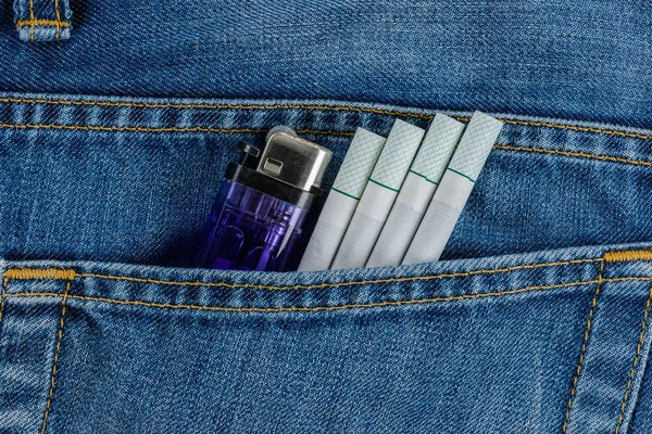 Cigarettes and cheap lighter in old blue denim jeans pocket