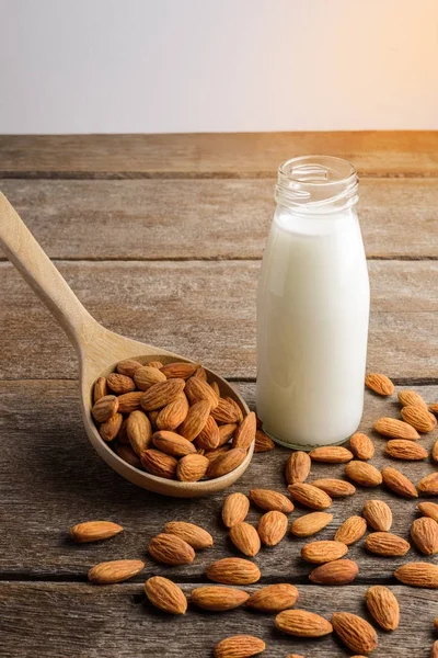 Mandelmilch in Flasche mit Mandeln aus Holzlöffel gießen — Stockfoto