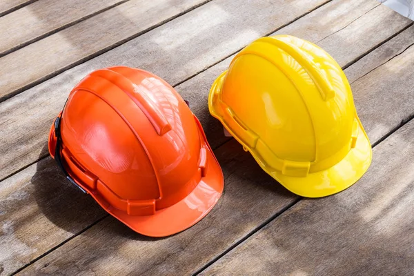 エンジニアまたは労働者 エンジニア リングの建設労働者等木質系床として職人の安全プロジェクトの黄色 オレンジ色のハード安全ヘルメット建設帽子 — ストック写真