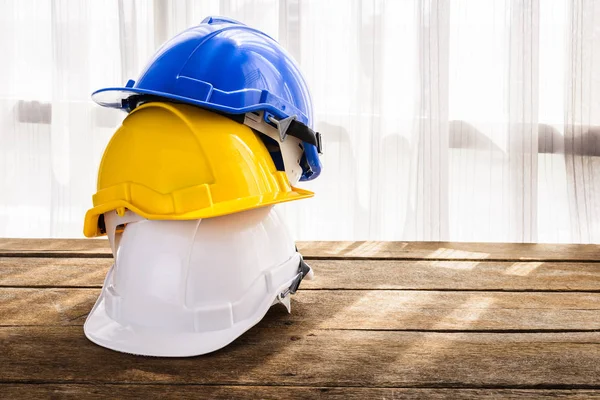 技術者や労働者 エンジニア リングの建設労働者等 木の床 窓の光カーテンとして職人の安全プロジェクトの青 白のハード安全ヘルメット建設帽子は背景 — ストック写真