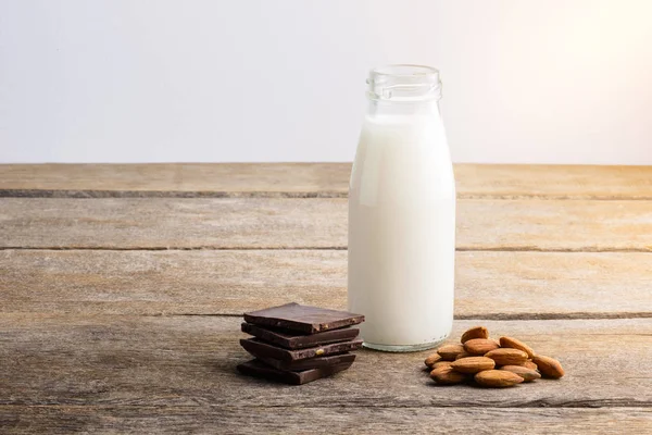 Mléko láhev, čokoláda a mandle na dřevěné — Stock fotografie