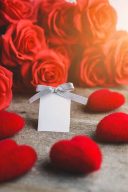 Kırmızı güller, kırmızı kalp ve beyaz etiket ahşap bir masa kartına
