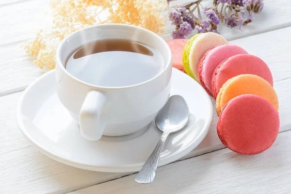 Différents types de couleurs de macarons avec tasse de thé chaud sur blanc — Photo