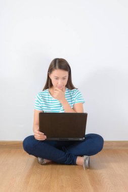 dizüstü bilgisayar ile katta oturan genç yaratıcı kadın