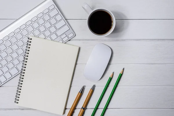 Hölzerner weißer Schreibtisch mit Tasse Kaffee, Notizbuch, Stift — Stockfoto