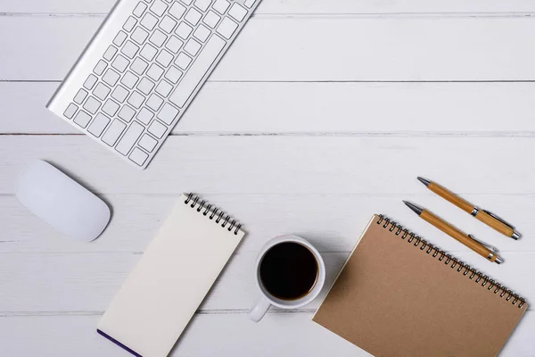 Hölzerner weißer Schreibtisch mit Tasse Kaffee, Notizbuch, Stift — Stockfoto