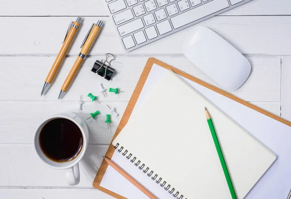 Hölzerner weißer Schreibtisch mit Tasse Kaffee, Notizbuch, Stift — Stockfoto