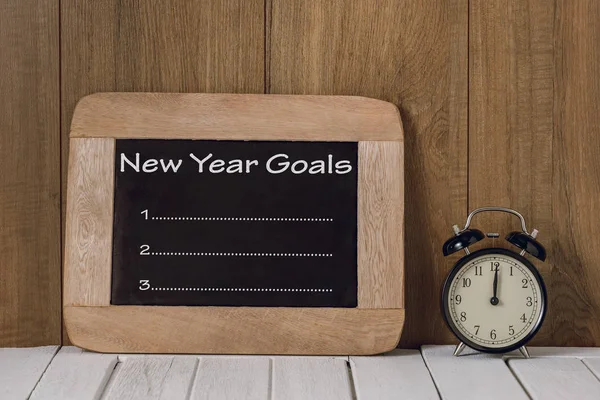 Lista de Metas de Ano Novo escrito em quadro-negro com relógio de alarme — Fotografia de Stock