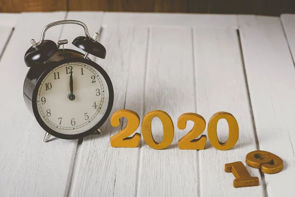 Alarm clock 2020 Wooden gold number.  Happy New Year on nature c