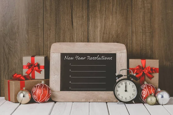 Reloj despertador con adornos navideños y resoluciones de Año Nuevo —  Fotos de Stock