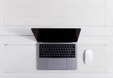 Düz yatıyordu, ahşap ofis masasının üstünde. Dizüstü bilgisayarlı çalışma alanı, fare ofis malzemeleri beyaz ahşap masa arka planında coppy alanı