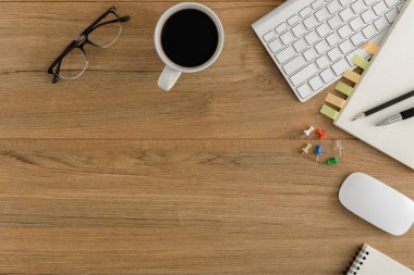 Düz yatıyordu, ahşap ofis masasının üstünde. Çalışma alanı boş defter, klavye, fare bilgisayarı, kalem, gözlük ofis gereçleri ahşap masa zemininde coppy alanı