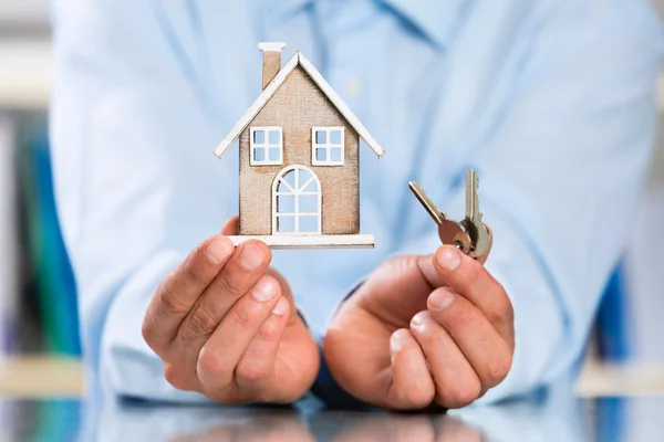 Męskie ręce trzymając miniaturowe House i House klucz — Zdjęcie stockowe