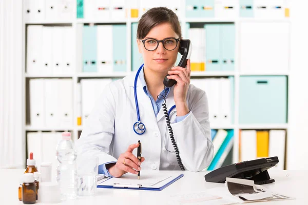 Női orvos, íróasztal, telefon — Stock Fotó