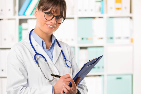 Médico sonriente con portapapeles y pluma — Foto de Stock