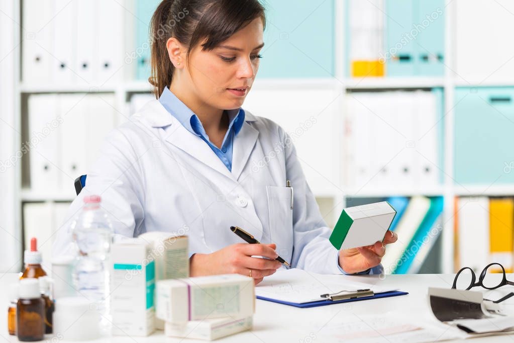 Female pharmacist sat at desk writing notes