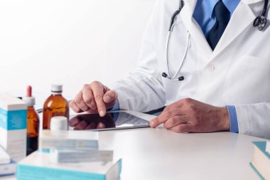 Dijital tablo kullanarak masasında stetoskop ile erkek doktor el