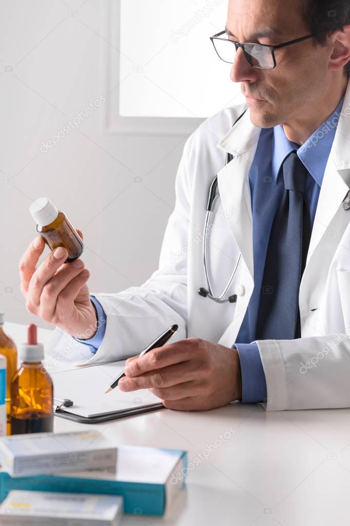 male pharmacist sat at desk reading notes