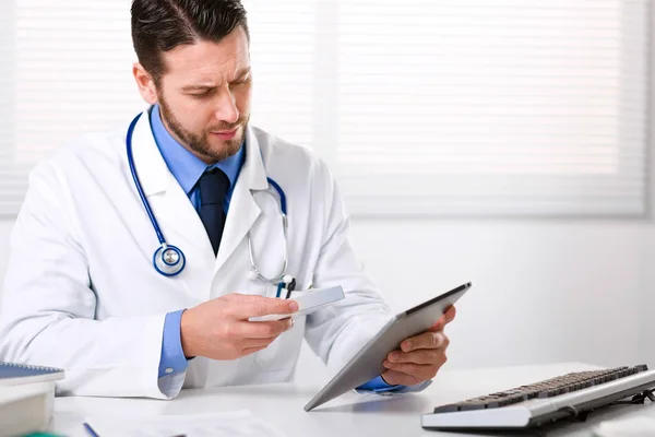 Доктор тримає планшет і коробку ліків — стокове фото