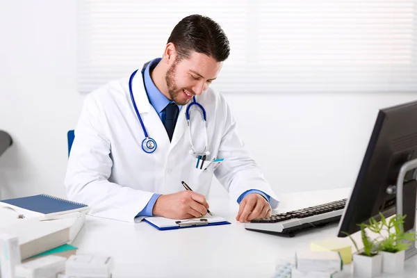 Usmívající se muž lékař psaní poznámek — Stock fotografie
