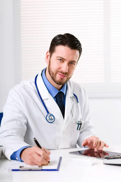 Médico à mesa olhando para a câmera — Fotografia de Stock