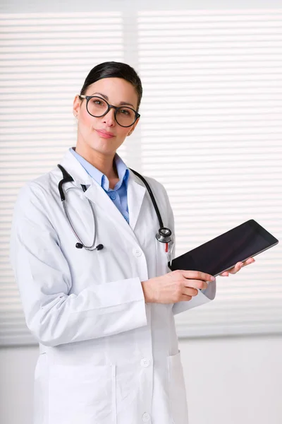 Жінка-лікар стоїть і працює з планшетом — стокове фото