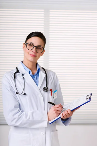 Женщина-врач стоит и пишет на планшете — стоковое фото