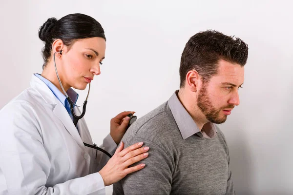 Dokter wanita muda mendengarkan detak jantung — Stok Foto