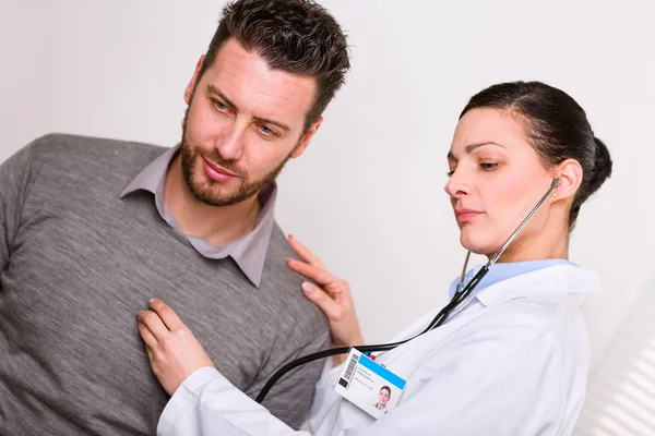 Dokter wanita muda mendengarkan detak jantung — Stok Foto