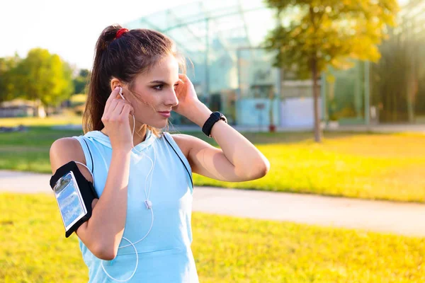 スポーティな女性がイヤホンで音楽を聴く — ストック写真