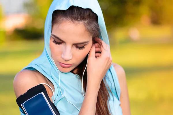 Vrouw met capuchon luisteren naar muziek van haar Smartphone — Stockfoto