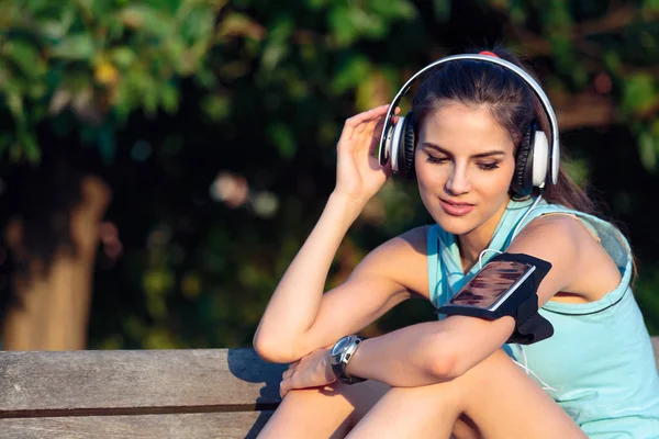 Žena poslechu hudby se sluchátky od svého chytrého telefonu — Stock fotografie
