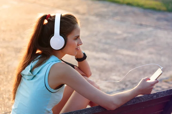 Žena poslechu hudby se sluchátky od svého chytrého telefonu — Stock fotografie