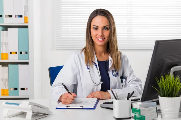 Жінка-лікар сиділа за столом з папками на задньому плані — стокове фото