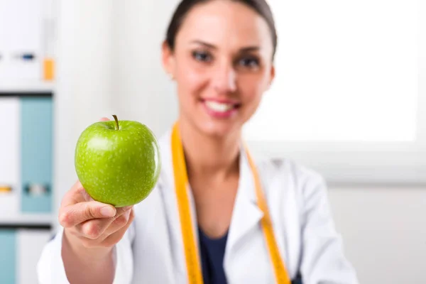 Женщина-диетолог дарит зеленое яблоко — стоковое фото
