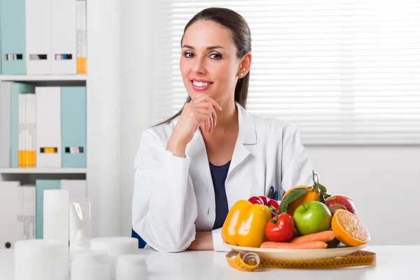 Женский диетолог показывает овощи и фрукты — стоковое фото