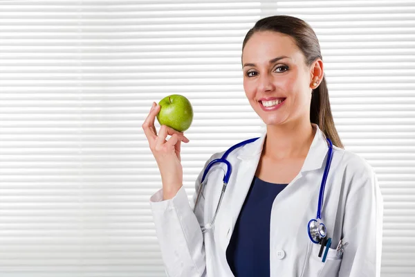 Женщина-диетолог держит зеленое яблоко — стоковое фото