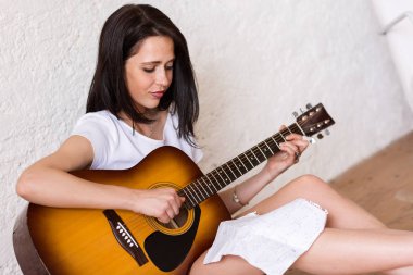 Kadın akustik gitar çalıyor.