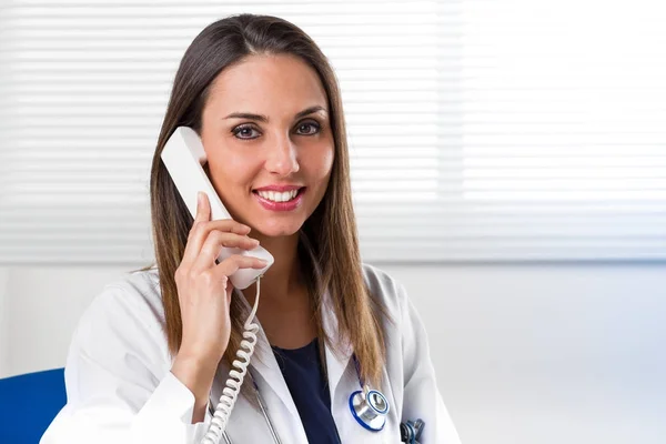 Smiling female Doctor with telephone to ear — Stock Photo, Image