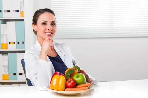 Женский диетолог показывает овощи и фрукты — стоковое фото