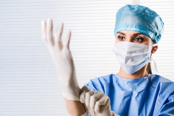 Γυναίκα γιατρός χειρουργός βάζοντας σε χειρουργικά γάντια — Φωτογραφία Αρχείου