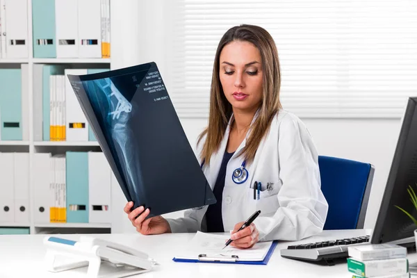 Female doctor looking at patients x-ray in her office — Stock Photo, Image