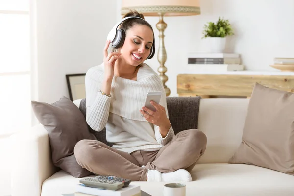 Žena poslech hudby ve sluchátkách na gauči — Stock fotografie
