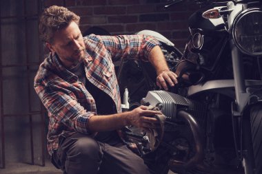 Bir motosiklet üzerinde çalışan tahsildar ya da tamirci