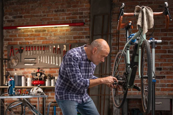 ワークショップで屋内で自転車に取り組む男 — ストック写真