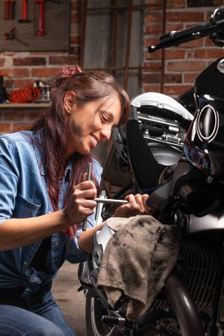 Klasik bir motosiklet üzerinde çalışan kadın tamirci.