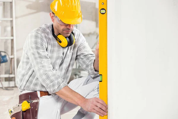 Constructor usando un nivel de espíritu para medir una pared — Foto de Stock