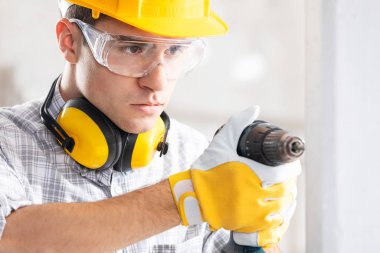 Builder drilling a hole in a new wall