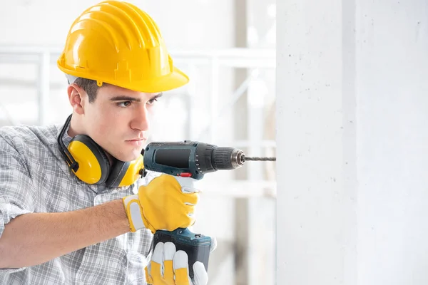 Constructor perforando un agujero en una nueva pared — Foto de Stock