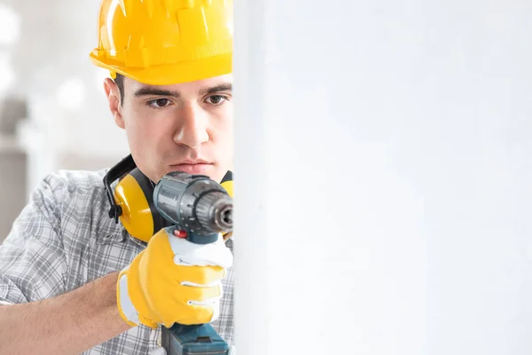 Jovem trabalhador da construção do sexo masculino perfuração da parede — Fotografia de Stock